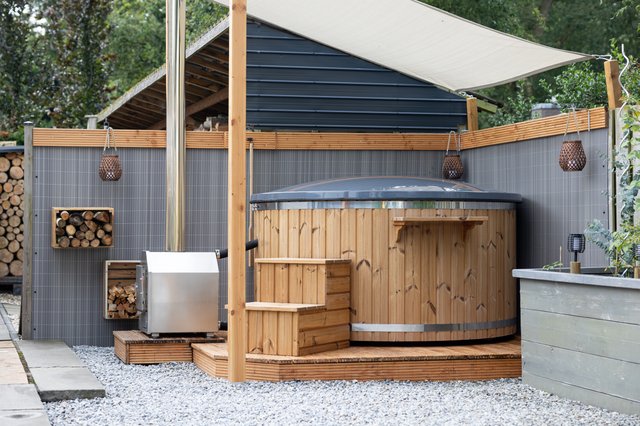 Houten hottub met grijze afdekking op een houten platform in een tuin