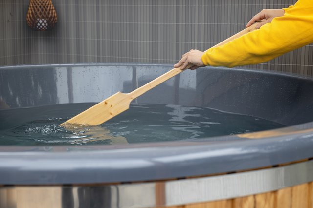 Houten peddel in een hottub, bediend door persoon in gele trui